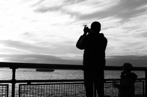 Man silhouetted with child looking out at the Statue of Liberty