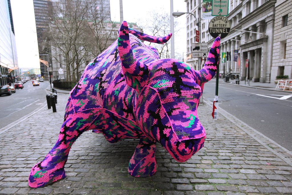 Wall street bull statue yarn bombed with crochet pink and purple coat
