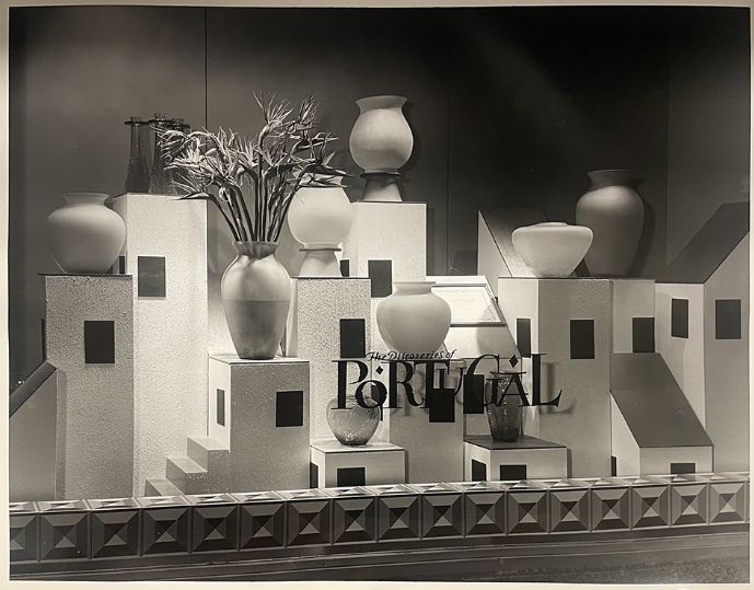 Black and white photograph of Bloomingdale's Portugal-themed window display with large ceramic vases sitting on top of a cityscape of white architectural model buildings