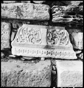 Black and white photo of ancient capital built into later stone wall