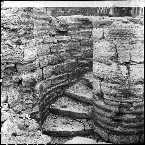 Black and white photo of ancient circular staircase in ruined walls