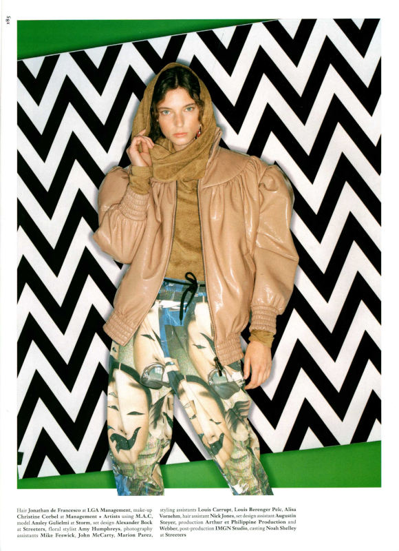 Model in tan leather jacket, big art print pants in front of a bold graphic backdrop