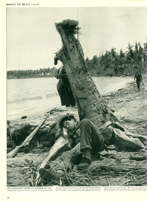 A soldier sleeps on a recently bombed beach